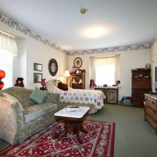 A cozy bedroom with vintage decor, featuring a bed, sofa, and various decorative items.