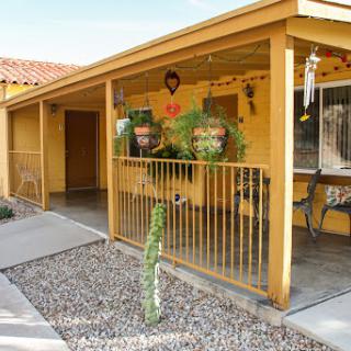 A welcoming yellow house with a charming porch adorned with plants and decorative elements.