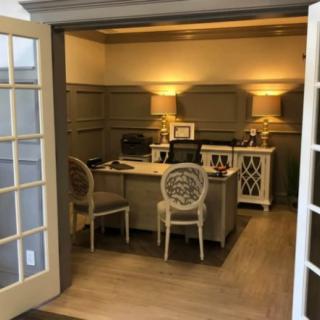 A cozy office space with a desk and chairs, softly lit by table lamps.