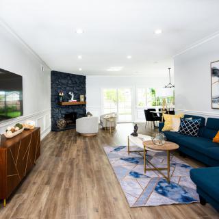 A modern living room with a blue sofa, wooden flooring, and a cozy fireplace.