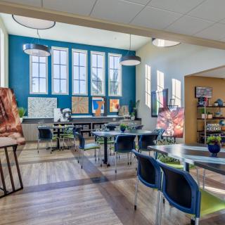A modern classroom with large windows, bright lighting, and organized desks and chairs.