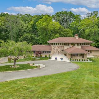 A large house surrounded by lush greenery with a spacious driveway.