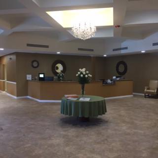 A spacious lobby featuring a central table with floral arrangements and a chandelier.