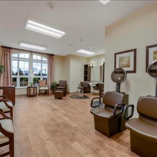 A modern salon interior featuring comfortable chairs and hair dryers, with large windows providing natural light.