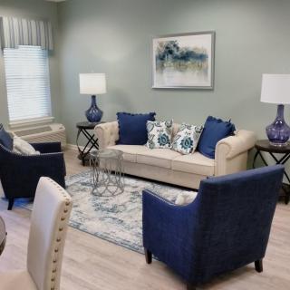 A cozy living room with a neutral-colored sofa, blue armchairs, and matching decor accents.