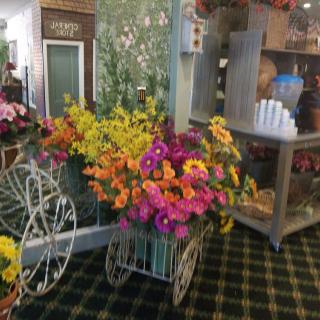 A decorative display of colorful flowers arranged in a vintage-style cart indoors.