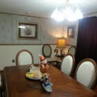 A warmly lit dining room with a wooden table, surrounded by cushioned chairs and decorated with ornaments.