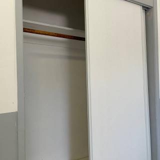 An empty closet with a sliding door and a wooden rod.