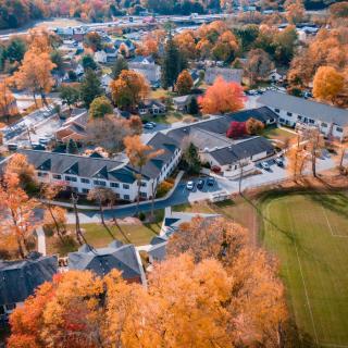 Aerial view of a suburban neighborhood showcasing vibrant autumn foliage and scattered buildings.