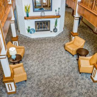 A cozy lobby seating area with upholstered chairs and a central fireplace.