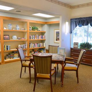 A cozy library reading room with bookshelves, a table, and chairs.