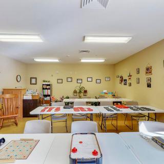 A classroom with tables and chairs arranged for activities, adorned with wall decorations and games.