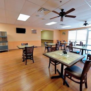 An empty restaurant dining area with hardwood flooring and neatly arranged tables and chairs.