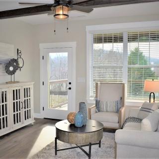 A modern living room with neutral colors, featuring comfortable furniture and ample natural light through large windows.