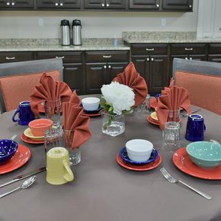 A neatly arranged table setting with colorful tableware and folded napkins in a kitchen setting.