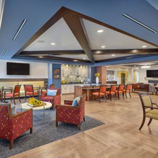 A modern and spacious lounge area with comfortable seating, tables, and a blue accented ceiling.
