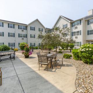 A serene courtyard with outdoor seating surrounded by greenery and a multi-story building.