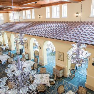 A luxurious dining room with elegant chandeliers, beautifully set tables, and arched windows.