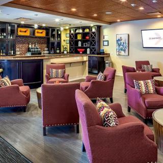 A cozy lounge area featuring comfortable red armchairs and a well-stocked bar.