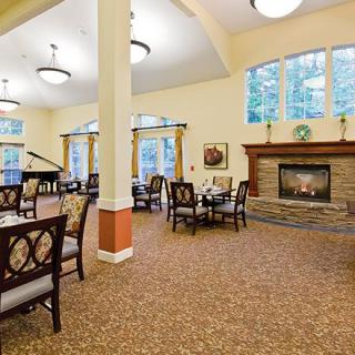 A cozy dining area with a fireplace and a grand piano.