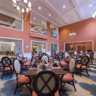 An elegant and spacious dining room with arranged tables and chandeliers.