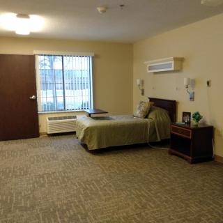 A simple bedroom with a bed, nightstand, and large window.