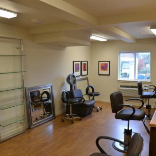 An empty hair salon with chairs and mirrors.