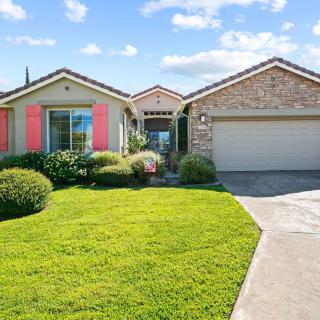 A charming suburban house with a well-maintained lawn and garden on a sunny day.
