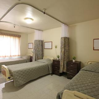 A hospital room with two beds and privacy curtains.