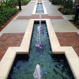 A serene outdoor setting featuring a modern water fountain along a pathway.