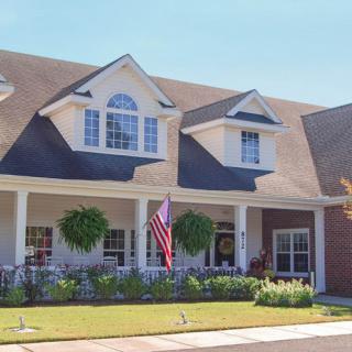 A charming suburban house with a porch and American flag in the yard.