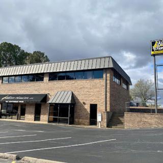 A brick restaurant building with a parking lot under a cloudy sky.
