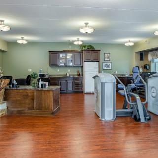 A spacious and well-lit fitness room featuring exercise equipment and a kitchenette.