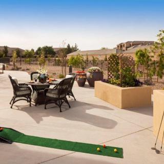 A sunny outdoor patio with a dining set and a small golf putting area.