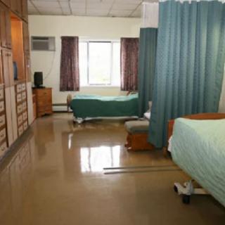 A hospital room with two beds separated by a curtain.