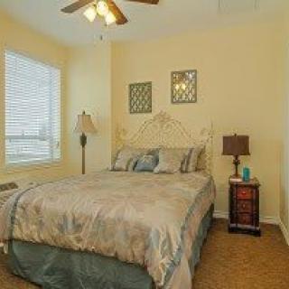 Cozy bedroom with a bed, bedside tables, and a lamp near a window.