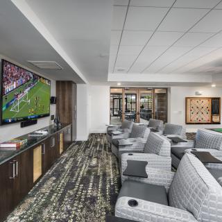 A luxurious lounge area with comfortable seating and a large TV displaying a sports game.