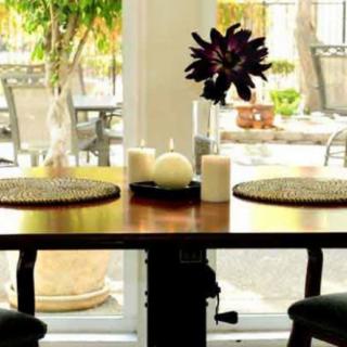 A cozy dining setup with candles and flowers by a window.