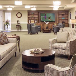 A cozy living room with comfortable seating arrangements and bookshelves in the background.
