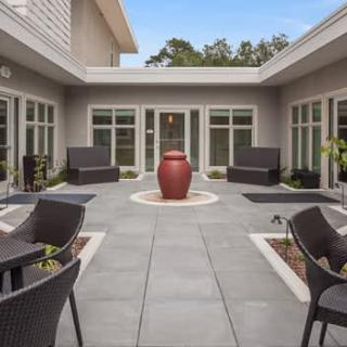 A modern courtyard with outdoor seating and a central red vase.