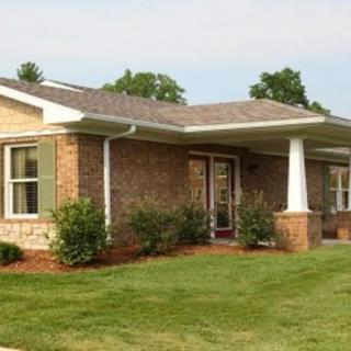A single-story brick house with a well-maintained lawn and landscaping.
