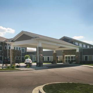 A modern building with a covered entrance and parking area.