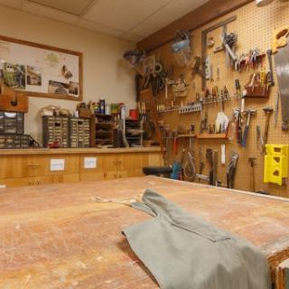 A well-organized woodworking workshop featuring various hand tools and a spacious workbench.