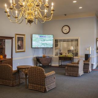 A cozy lobby with a chandelier, seating area, and television.