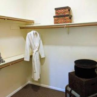 A spacious closet with shelves, a hanging robe, and storage boxes.