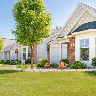 A row of suburban houses with well-maintained lawns and trees.