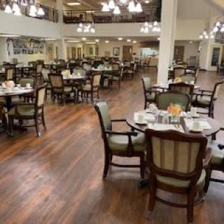 A spacious dining room with elegant tables and chairs, illuminated by chandeliers.