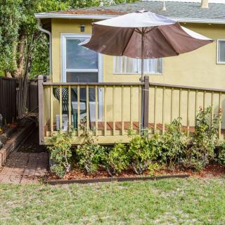 A cozy backyard with a wooden deck and patio umbrella, featuring a small garden and landscaping.