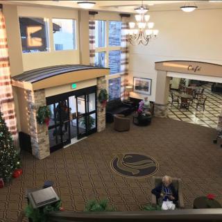 A hotel lobby featuring a decorated Christmas tree, seating area, and chandelier.