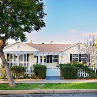A charming, single-story house with a welcoming front porch and well-maintained landscaping.
